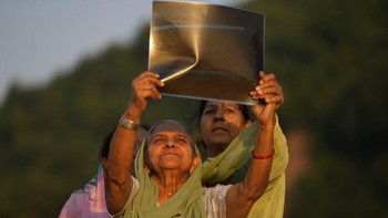 Tua maupun muda sama-sama antusias menyaksikan gerhana matahari parsial berbekal lembaran film agar tak merusak mata di tepi Sungai Tawi di Jammu, India. Foto: AP/Hassan Ammar