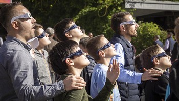 Para siswa dan guru di sebuah sekolah di Pristina, Kosovo, ramai-ramai menyaksikan gerhana Matahari menggunakan kacamata khusus. Foto: AP/Hassan Ammar