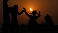 Gerhana matahari sebagian dibingkai oleh gadis-gadis muda yang melompat di atas trampolin di pinggiran Lahore, Pakistan, Selasa (25/10/2022). Gerhana itu mulai sejak 25 Oktober 2022 pukul 08.58.21 UT atau 15.58.21 WIB dan berakhir pada pukul 13.02.18 UT atau 20.02.18 WIB. (AP Photo/K.M. Chaudary)  