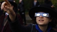 Seorang wanita melihat matahari melalui kacamata khusus selama gerhana matahari sebagian di Warsawa, Polandia, Selasa, Selasa (25/10/2022). (AP Photo/Michal Dyjuk)  