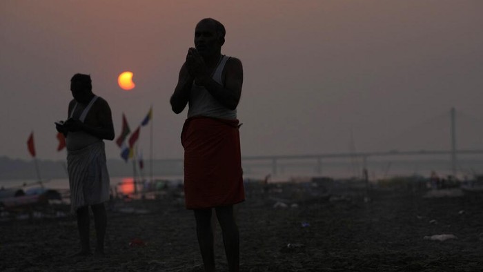Melihat Gerhana Matahari Sebagian dari Berbagai Negara Umat Hindu melakukan ritual di Sangam, selama gerhana matahari sebagian di Prayagraj, negara bagian utara Uttar Pradesh, India, Selasa (25/10/2022). Fenomena gerhana matahari sebagian terjadi pada 25 Oktober 2022 dan bisa dilihat di sejumlah negara. (AP Photo/Rajesh Kumar Singh)
