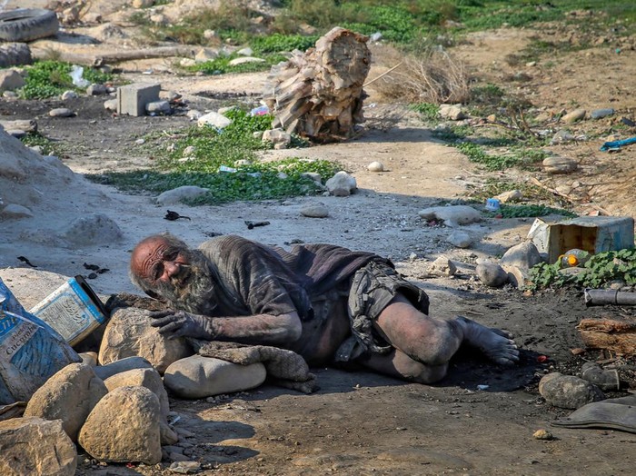 Amou Haji (uncle Haji) smokes from his waterpipe as he sits on the ground on the outskirts of the village of Dezhgah in the Dehram district of the southwestern Iranian Fars province, on December 28, 2018. - Believed to be the worlds dirtiest man, villagers say that Haji's leather-like skin hasn't touched soap and water for more than sixty years. They believe that he decided to live in isolation after suffering from an emotional setback in his youth. (Photo by - / AFP) (Photo by -/AFP via Getty Images)
