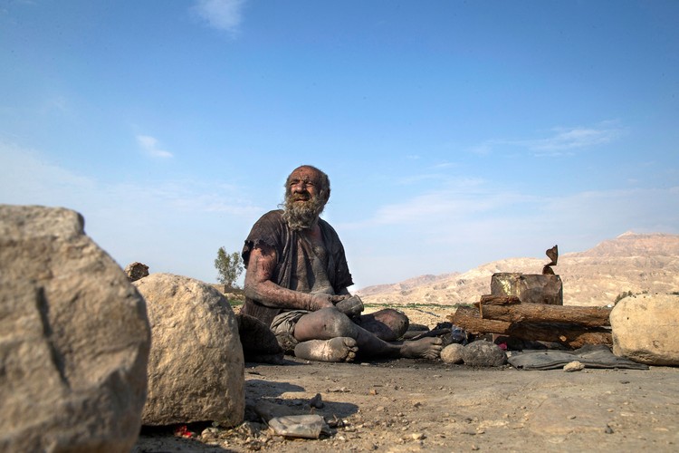Amou Haji (uncle Haji) smokes from his waterpipe as he sits on the ground on the outskirts of the village of Dezhgah in the Dehram district of the southwestern Iranian Fars province, on December 28, 2018. - Believed to be the worlds dirtiest man, villagers say that Hajis leather-like skin hasnt touched soap and water for more than sixty years. They believe that he decided to live in isolation after suffering from an emotional setback in his youth. (Photo by - / AFP) (Photo by -/AFP via Getty Images)