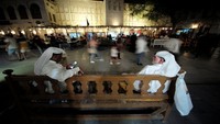 Dua warga Doha duduk sambil menikmati suasana malam yang ramai di kawasan pasar tradisional Souq Waqif di Kota Doha, Qatar, Minggu, (23/10/2022).