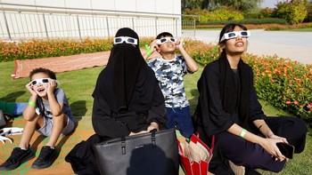 Orang-orang menyaksikan gerhana Matahari sebagian menggunakan kacamata khusus di Pusat Astronomi Al Thuraya di Dubai, Uni Emirat Arab. Foto: AP/Victor Berezkin