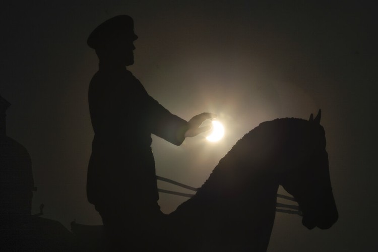 The moon covering part of the sun, during a partial solar eclipse at the monument of Soviet Marshal Georgy Zhukov in Moscow, Russia, Tuesday, Oct. 25, 2022. (AP Photo/Victor Berezkin)