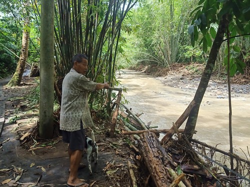 Salah seorang warga Banjar Sekarkejula Kelod, Desa Yehembang Kauh, Mendoyo, Jembrana, Bali, menunjukan kondisi jembatan darurat yang rusak diterjang banjir, Rabu (26/10/2022).