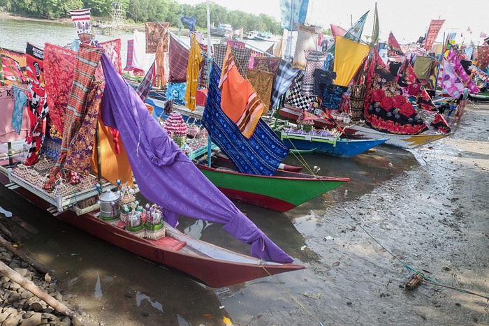 People carry a boat decorated with clothes as part of an annual tradition to celebrate the Islamic Prophet Muhammads birthday in Takalar, South Sulawesi on October 25, 2022. (Photo by INDRA ABRIYANTO / AFP) (Photo by INDRA ABRIYANTO/AFP via Getty Images)