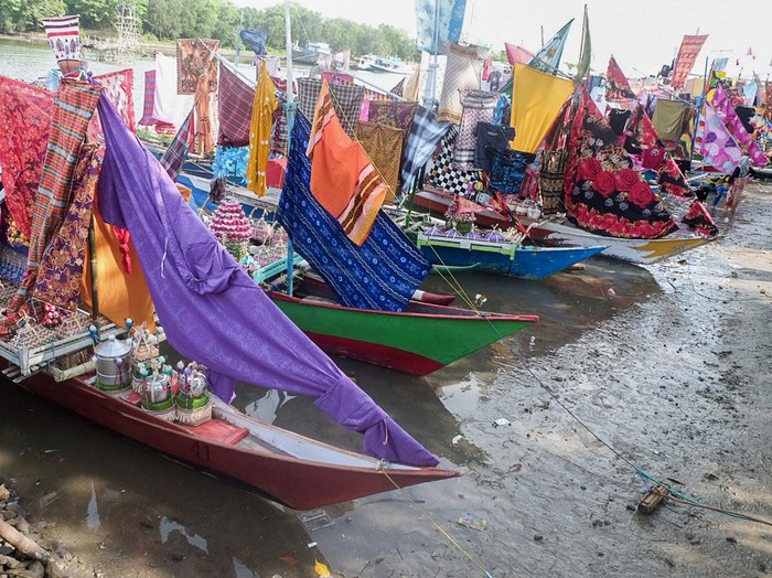 People carry a boat decorated with clothes as part of an annual tradition to celebrate the Islamic Prophet Muhammads birthday in Takalar, South Sulawesi on October 25, 2022. (Photo by INDRA ABRIYANTO / AFP) (Photo by INDRA ABRIYANTO/AFP via Getty Images)