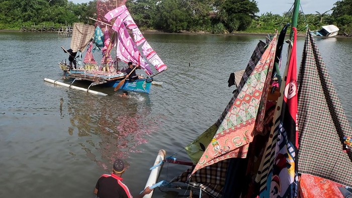 People carry a boat decorated with clothes as part of an annual tradition to celebrate the Islamic Prophet Muhammads birthday in Takalar, South Sulawesi on October 25, 2022. (Photo by INDRA ABRIYANTO / AFP) (Photo by INDRA ABRIYANTO/AFP via Getty Images)