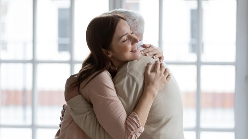 Grownup daughter straining to heart dear senior dad meeting after long time separation. Tender young woman adult grandkid cuddling with warmth elderly man grandfather greeting with birthday father day
