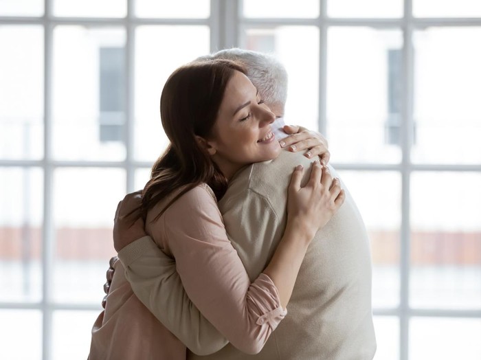 Grownup daughter straining to heart dear senior dad meeting after long time separation. Tender young woman adult grandkid cuddling with warmth elderly man grandfather greeting with birthday father day