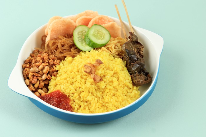 A Plate of Nasi Kuning or Yellow Rice, Favorite Indonesian Menu for Breakfast. Popular Street Food, Yellow Color came from Turmeric