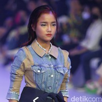 Fuji memakai skirt denim daur ulang, blazer yang diikat di pinggang dan celana pendek potongan longgar. Penampilan Fuji yang menjadi model langsung menjadi sorotan. Ia catwalk dengan rasa percaya diri dan tatapan yang tajam. Fuji berjalan sambil memasukkan tangan ke dalam saku.  Foto: Agung Pambudhy/Detikcom.