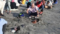 Para orang tua mendampingi anaknya yang dikubur sebagian tubuhnya saat gerhana matahari. Sabir Mazhar/Anadolu Agency/Getty Images