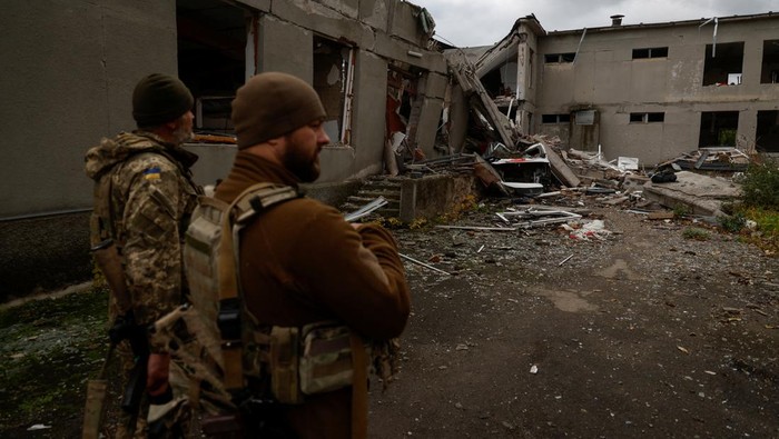 Ukrainian servicemen stand next to a school building destroyed by a Russian air strike in a village near a frontline in Mykolaiv region, Ukraine October 26, 2022. REUTERS/Valentyn Ogirenko