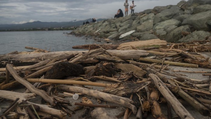 Warga berjalan di tanggul batu gajah Pantai Talise, Teluk Palu Palu, Sulawesi Tengah, Kamis (27/10/2022). Kawasan tersebut dikotori sampah kiriman berupa potongan kayu dan plastik yang berasal dari luar pulau akibat terbawa arus saat musim angin barat selama periode Oktober hingga Desember. ANTARA FOTO/Basri Marzuki/rwa.