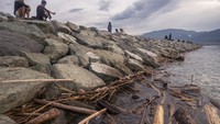 Warga menikmati suasana sore di tanggul batu gajah Pantai Talise yang dikotori sampah kiriman di Teluk Palu Palu, Sulawesi Tengah, Kamis (27/10/2022).