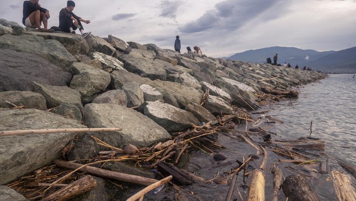SAMPAH KIRIMAN KOTORI TELUK PALU Warga berjalan di tanggul batu gajah Pantai Talise, Teluk Palu Palu, Sulawesi Tengah, Kamis (27/10/2022). Kawasan tersebut dikotori sampah kiriman berupa potongan kayu dan plastik yang berasal dari luar pulau akibat terbawa arus saat musim angin barat selama periode Oktober hingga Desember. ANTARA FOTO/Basri Marzuki/rwa.