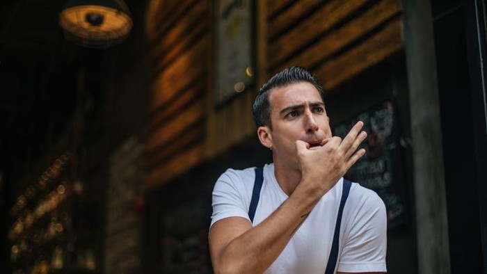 One man, young guy in cafe, he is on coffee break and whistling.