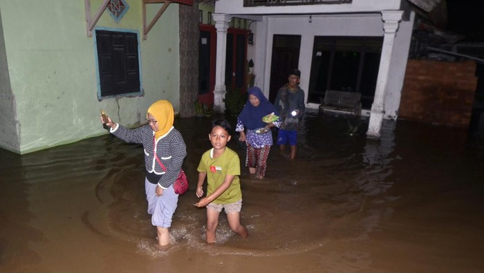Warga berjalan keluar dari rumahnya yang tergenang banjir akibat luapan Sungai Way Ketibung di Desa Beringin Kencana, Candipuro, Lampung Selatan, Lampung, Kamis (27/10/2022). Banjir tersebut terjadi akibat tanggul di sungai tersebut jebol dan merendam ratusan rumah penduduk, menyebabkan 200 orang mengungsi ke tempat yang lebih aman. ANTARA FOTO/Ardiansyah/wsj.