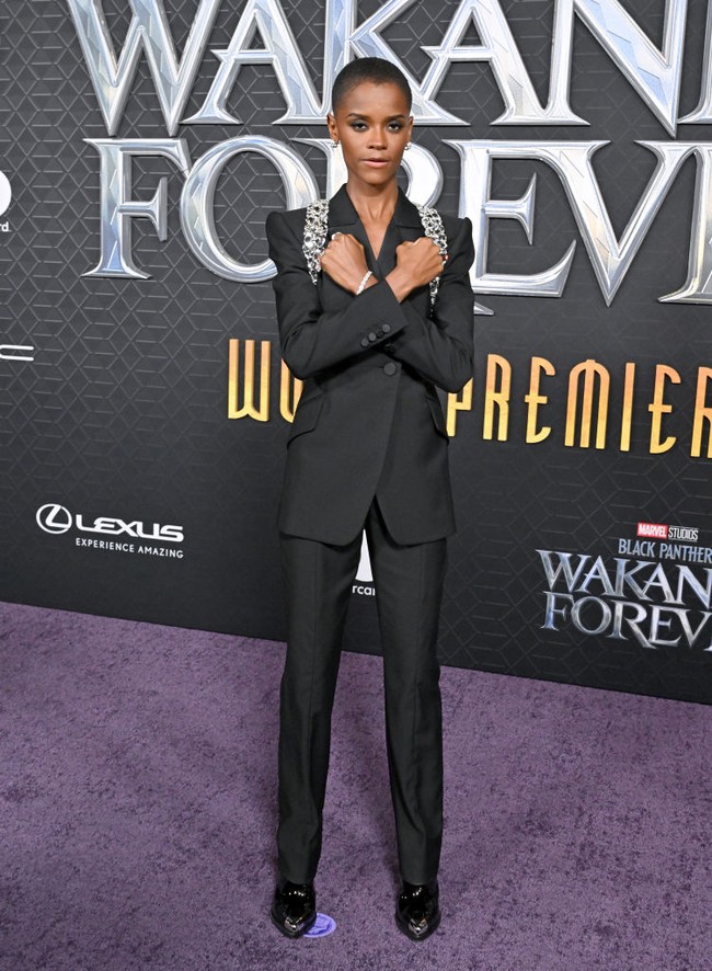 Letitia Wright memilih tampilan maskulin dengan setelan blazer hitam keluaran Alexander McQueen. Pemeran Shuri ini melengkapi gayanya dengan perhiasan statement. Foto: FilmMagic/Axelle/Bauer-Griffin
