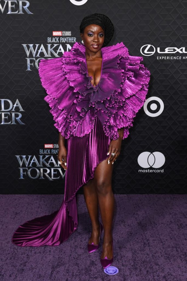 Danai Gurira tampil glamor nan dramatis dalam balutan gaun aksen pleats dan ruffle yang tampak seperti bunga sedang mekar. Gaun ungu metalik ini rancangan Robert Wun. Dalam sekuel Black Panther, Danai memerankan sosok ksatria wanita, Okoye. Foto: AFP via Getty Images/VALERIE MACON