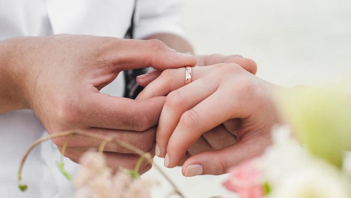 183273062 Husband and wife hands on wedding, holding flowers.