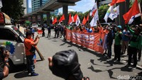 Massa demo sambil membawa atribut aksi berupa spanduk dan bendera organisasi buruh.
