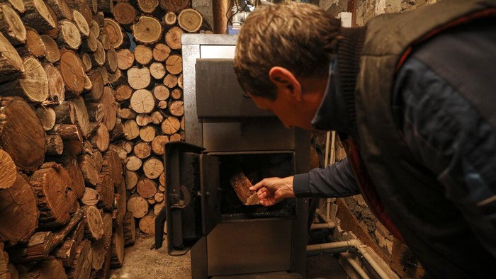 Potret Eropa Krisis Energi, Warga Beralih ke Kayu Bakar Tudor Popescu feeds firewood into a stove in a storage room attached to his home in Chisinau, Moldova, Saturday, Oct. 15, 2022. Europe's energy crisis, triggered by Russia slashing natural gas flows amid its war against Ukraine, has forced some people to turn to cheaper heating sources like firewood as the weather gets colder. But as more people stock up and burn wood, prices have skyrocketed, shortages and thefts have been reported, and scams are emerging. (AP Photo/Aurel Obreja)