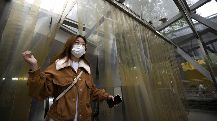 A commuter wearing a face mask walks out of a subway station in the central business district in Beijing, Friday, Oct. 28, 2022. (AP Photo/Mark Schiefelbein)