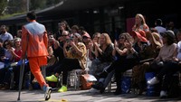 Model memakai tongkat saat memperagakan busana kreasi desainer Meksiko di sebuah catwalk. Penonton nampak antusias menyaksikan peragaan busana tersebut.