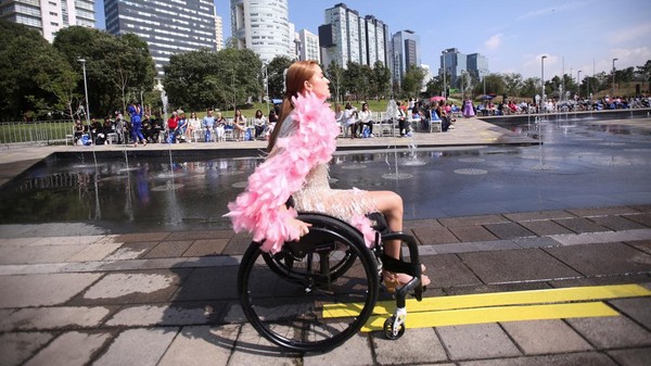 Model memakai kursi roda saat memperagakan busana kreasi desainer Meksiko di sebuah catwalk.