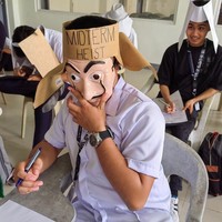 Bermodalkan topeng ala film Money Heist dan karton coklat tak terpakai, topi anti nyontek yang satu ini terlihat unik. Pada tahun 2013 sendiri Universitas Kasetsart di Thailand sempat viral karena menerapkan hal serupa. Foto: Instagram/@majjoymandz