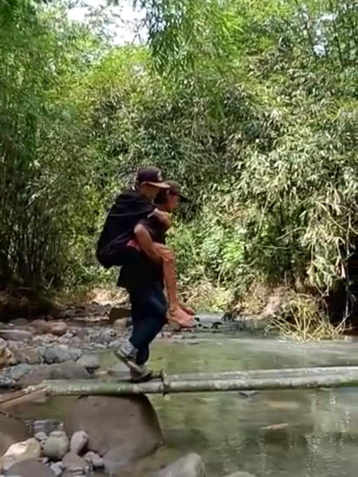 Warga Banjar Sekarkejula Kelod, Desa Yehembang Kauh, Mendoyo, Jembrana, Bali, gotong royong menggendong lansia agar bisa melintasi jembatan darurat. Warga Banjar Sekarkejula Kelod, Desa Yehembang Kauh, Mendoyo, Jembrana, Bali, gotong royong menggendong lansia agar bisa melintasi jembatan darurat.