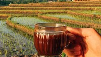  Secangkir kopi hangat jadi teman yang pas ketika melihat hamparan sawah di Tanah Lot, Bali. Foto: Instagram @girleatworld