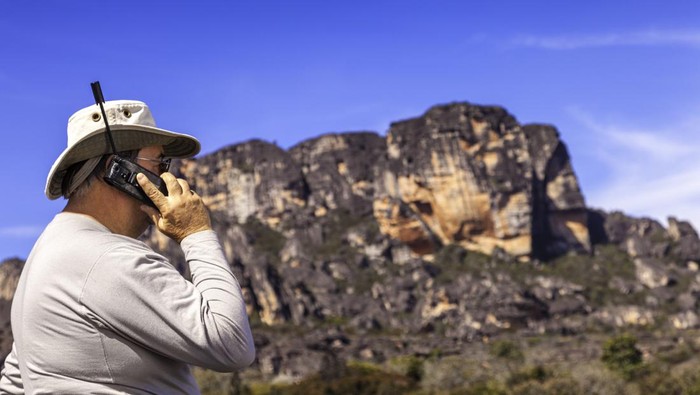 Mature explorer with a satellite portable phone at the Auyantepuy, Venezuela.
