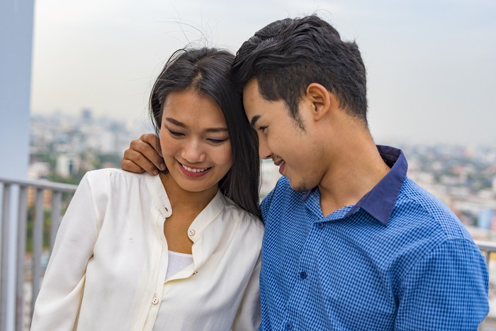 Young Asian couple hugging on a rooftop overlooking Bangkok