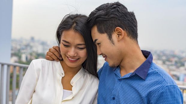 Young Asian couple hugging on a rooftop overlooking Bangkok