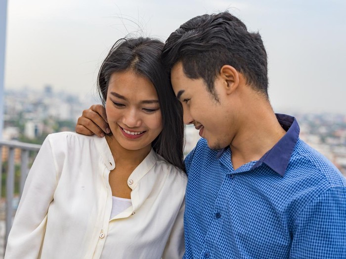 Young Asian couple hugging on a rooftop overlooking Bangkok