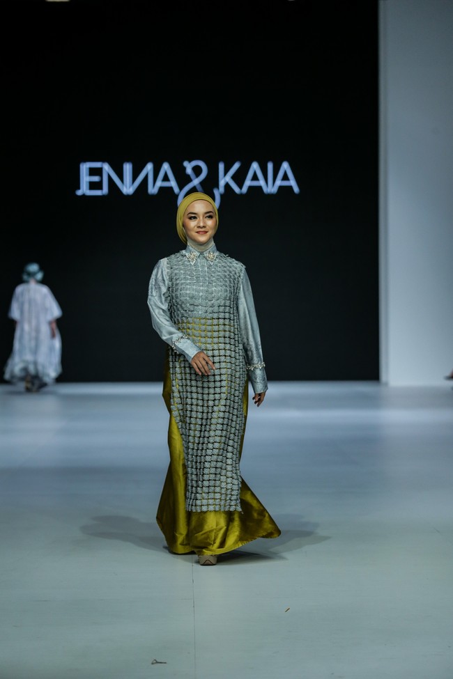 Titi Kamal berbagi panggung dengan Enno Lerian yang muncul dalam balutan gaun bernuansa abu-abu dengan aksen kuning-kehijauan. (Foto: Dachri Megantara/Jakarta Fashion Week)