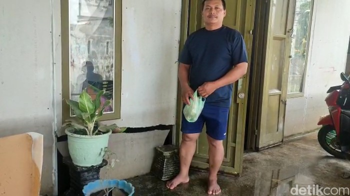 Warga saat menunjukkan dinding rumahnya yang jebol akibat banjir. (Nizar Aldi/detikSumut)