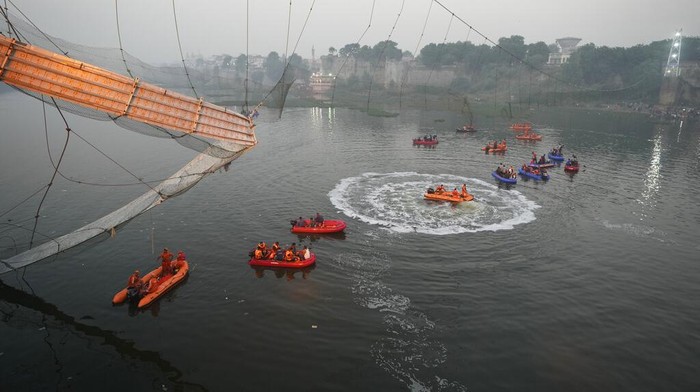 Kondisi Terkini Jembatan Ambruk di India, Korban Bertambah Jadi 132 Orang Search and rescue work is conducted after a cable suspension bridge collapsed in Morbi town of western state Gujarat, India, Monday, Oct. 31, 2022. The century-old cable suspension bridge collapsed into the river Sunday evening, sending hundreds plunging in the water, officials said. (AP Photo/Ajit Solanki)