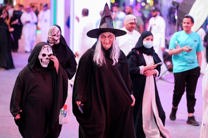 A Saudi man takes a photo with people dressed in costumes to celebrate Halloween during 
