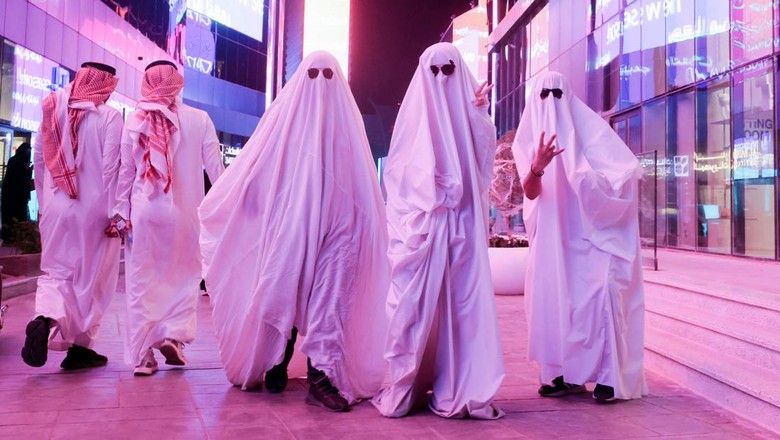 A Saudi man takes a photo with people dressed in costumes to celebrate Halloween during 
