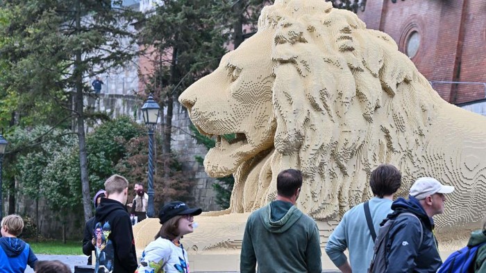 Wow... Patung Singa Ini Terbuat dari 850 Ribu Keping LEGO Tourists pose for photos in front of a giant Lego lion statue, a replica of one of the lion statues of the oldest bridge of Hungary - the Chain Bridge - in Budapest, on October 28, 2022. - The replica of the lion statues of the oldest bridge of Hungary, the Szechenyi Lanchid, was completed with 850 thousand Lego bricks in 560 hours by official Lego master builder and visual artist Balazs Doczy. The Lego lion was made on a scale of 1:1, the Lego statue is 5,80 meters long, 1,70 meters wide, 2,45 meters tall and weighs 1,3 tons. (Photo by ATTILA KISBENEDEK / AFP) (Photo by ATTILA KISBENEDEK/AFP via Getty Images)