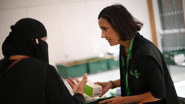 A member of staff (R) speaks with a member of the public inside a foodbank in Hackney, north-east London on October 31, 2022. - There were dozens of people on Monday queuing outside the Foodbank in Hackney, an east London district, with a voucher allowing them to obtain a basket containing three days' worth of food. (DANIEL LEAL/AFP via Getty Images)