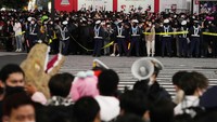 Petugas polisi mengendalikan orang-orang dengan kostum saat mereka menunggu untuk melewati persimpangan jalan yang terkenal di distrik hiburan Shibuya Tokyo selama perayaan Halloween, Senin, (31/10/2022). AP/Hiro Komae
