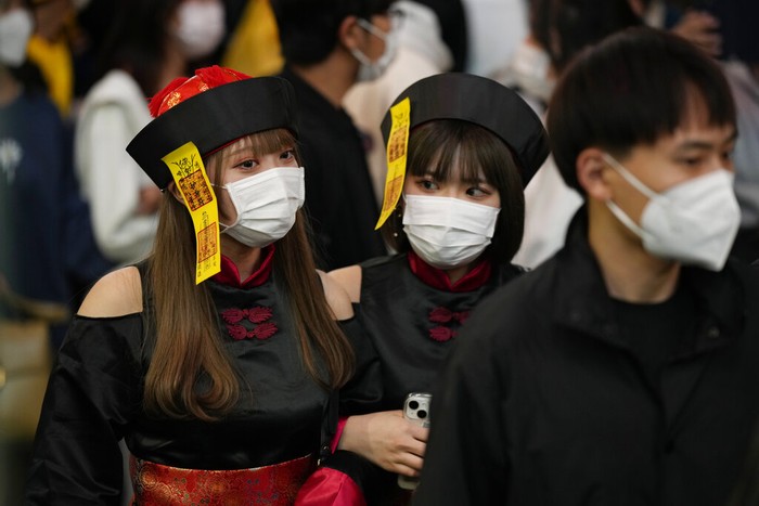 Police officers urge pedestrians in costumes to keep moving through the famed scramble intersection of Tokyos Shibuya entertainment district during Halloween festivities, Monday, Oct. 31, 2022. (AP Photo/Hiro Komae)