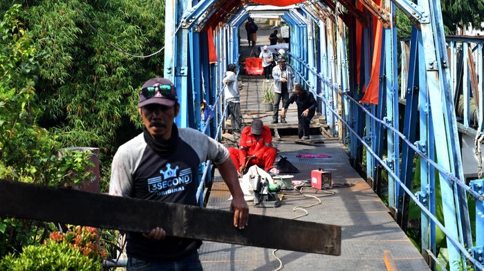 Pekerja memperbaiki jembatan ini dengan rangka dan plat besi yang nantinya akan menjadi akses jalan bagi warga di dua kelurahan di Kota Bogor.